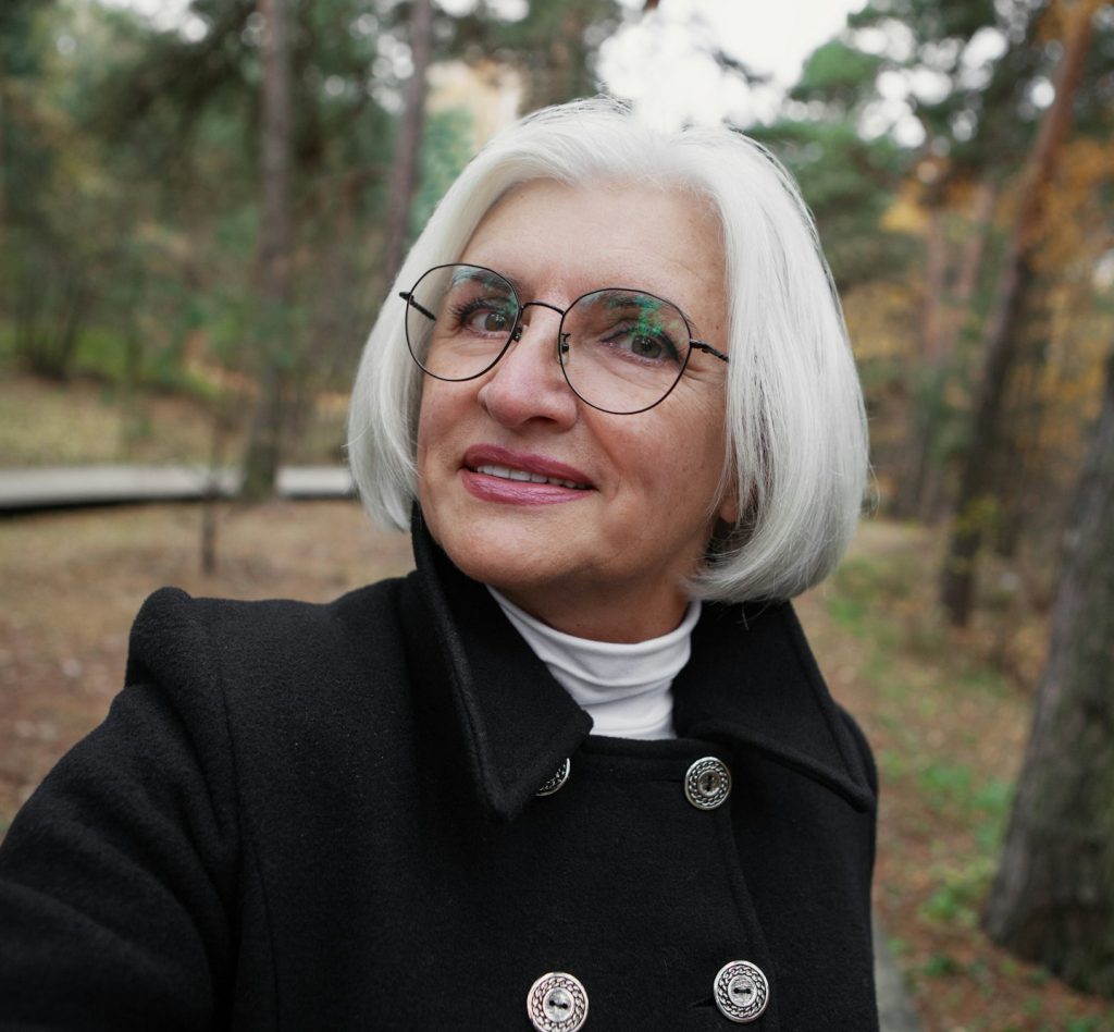 Authentic selfie portrait of senior 60 year old woman with gray hair and glasses