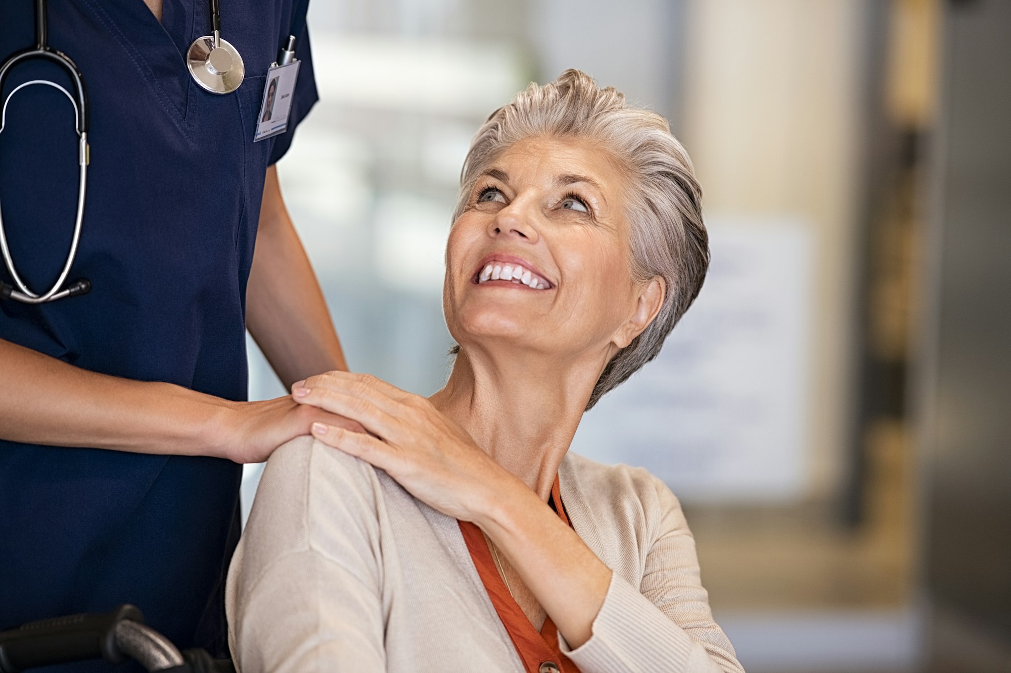 Caring nurse comforting old woman