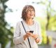 happy older woman laughing with mobile phone outside